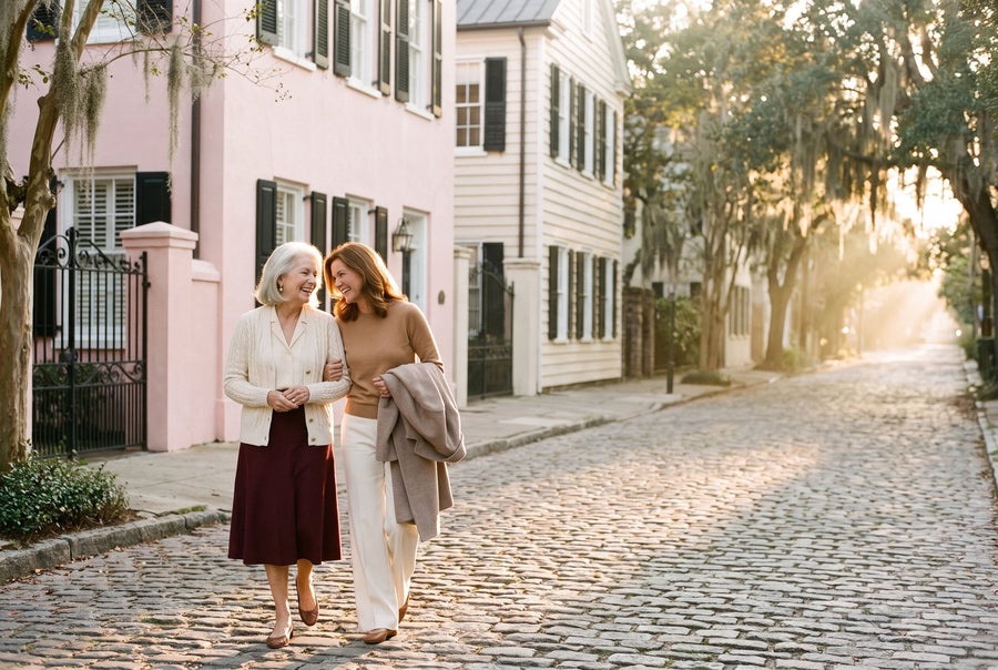 Harriet and June walking arm in arm past pastel row houses on a cobblestone lane